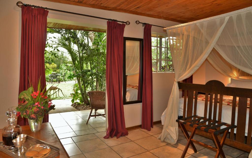 a bedroom with red curtains and a table and a bed at Kasane Self Catering in Kasane