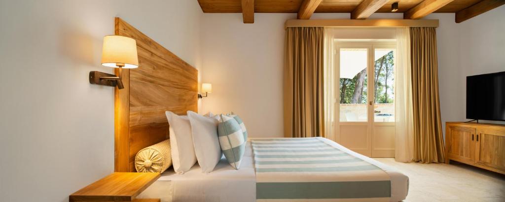 a bedroom with a bed with a television and a window at San Michele Relais & Spa in Sirolo