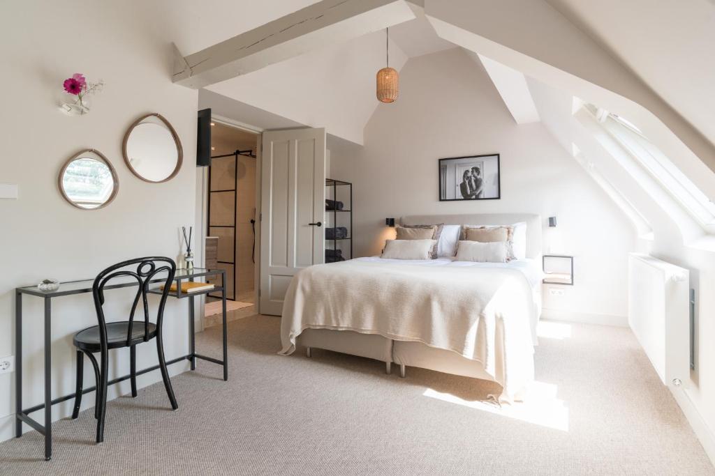 a white bedroom with a bed and a desk at Empire suites garden view in Amsterdam