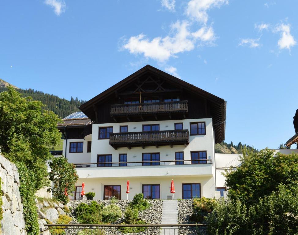 um grande edifício branco com um telhado preto em Hotel Garni Frommes em Fiss