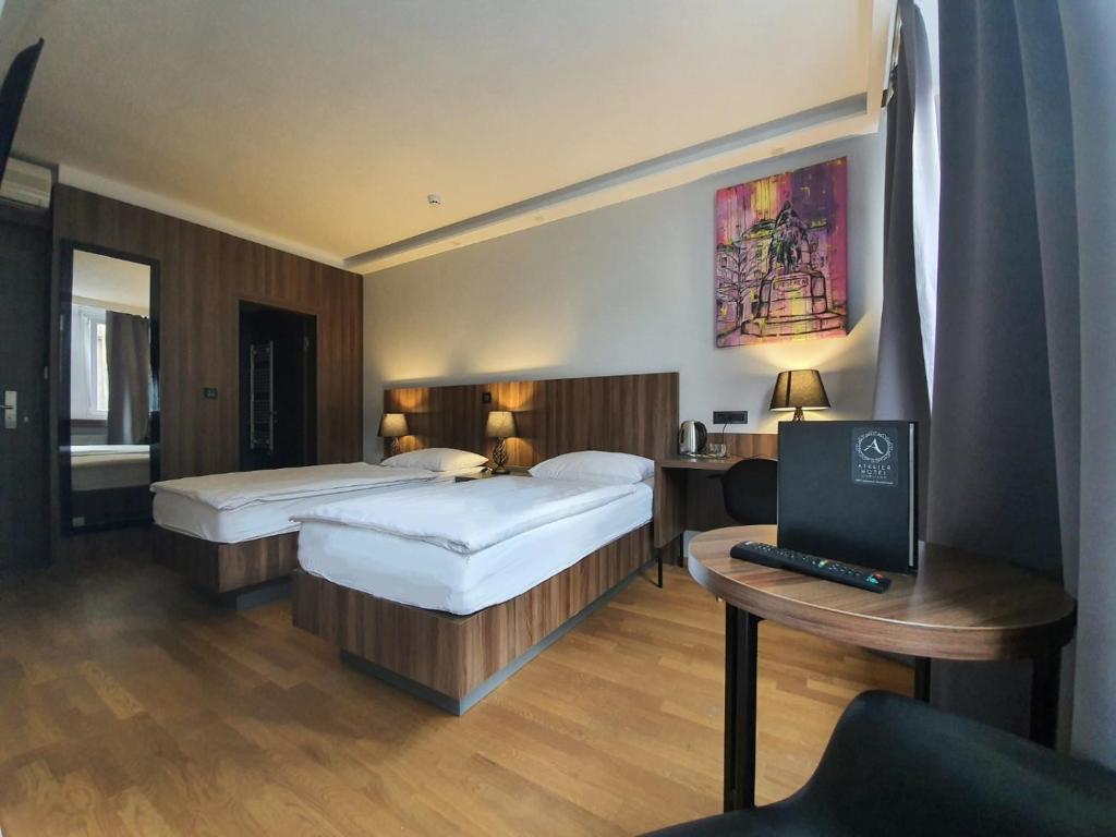 una camera d'albergo con 2 letti e una scrivania con un computer di Atelier Hotel a Lubiana