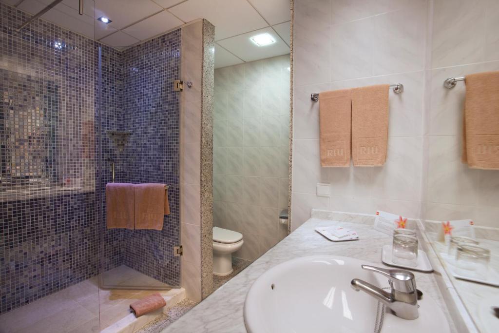 Un baño con lavabo, inodoro y ducha. en Hotel Riu Nautilus - Adults Only, en Torremolinos
