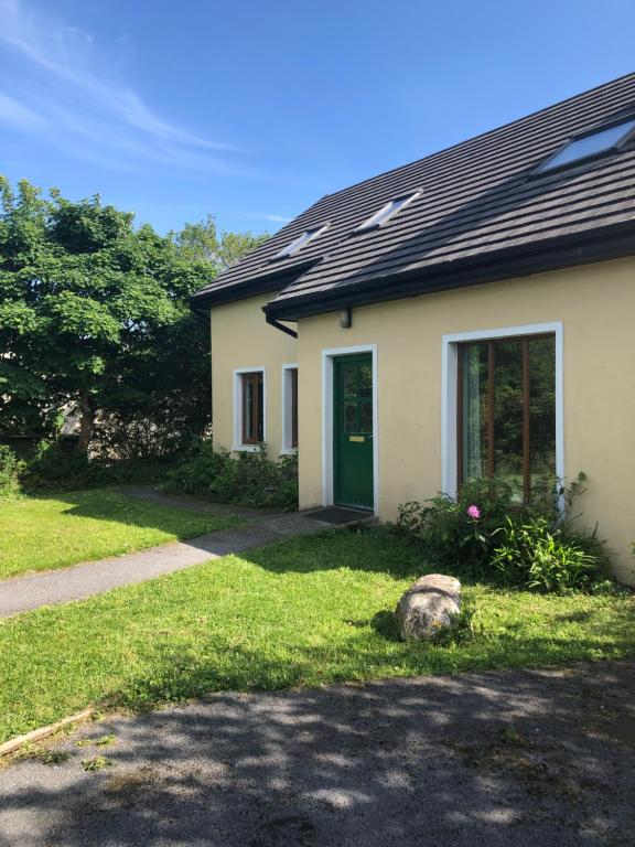 una casa con una puerta verde en el césped en Letterfrack Farm Lodge house in Letterfrack village Connemara en Letterfrack
