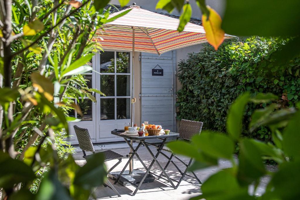 a table with an umbrella in front of a door at Hôtel Mas Valentine in Saint-Rémy-de-Provence