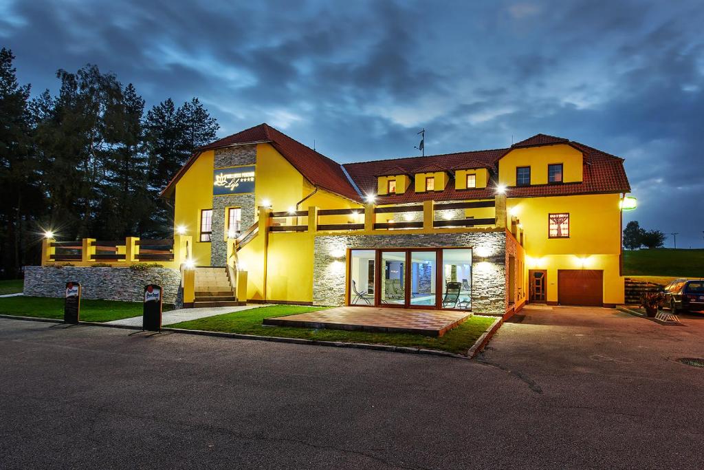a large yellow house with lights on at Wellness Penzion Life in Číměř