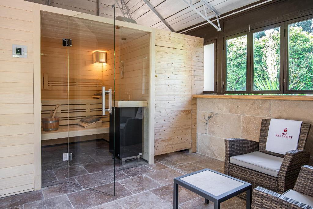 a living room with a tv and a chair and a table at Hôtel Mas Valentine in Saint-Rémy-de-Provence