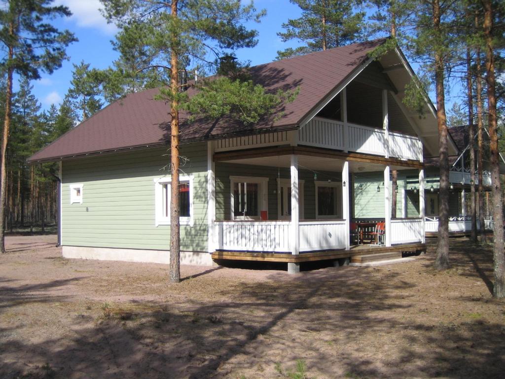 Casa verde y blanca con porche en Rattle Nest, en Loimaa