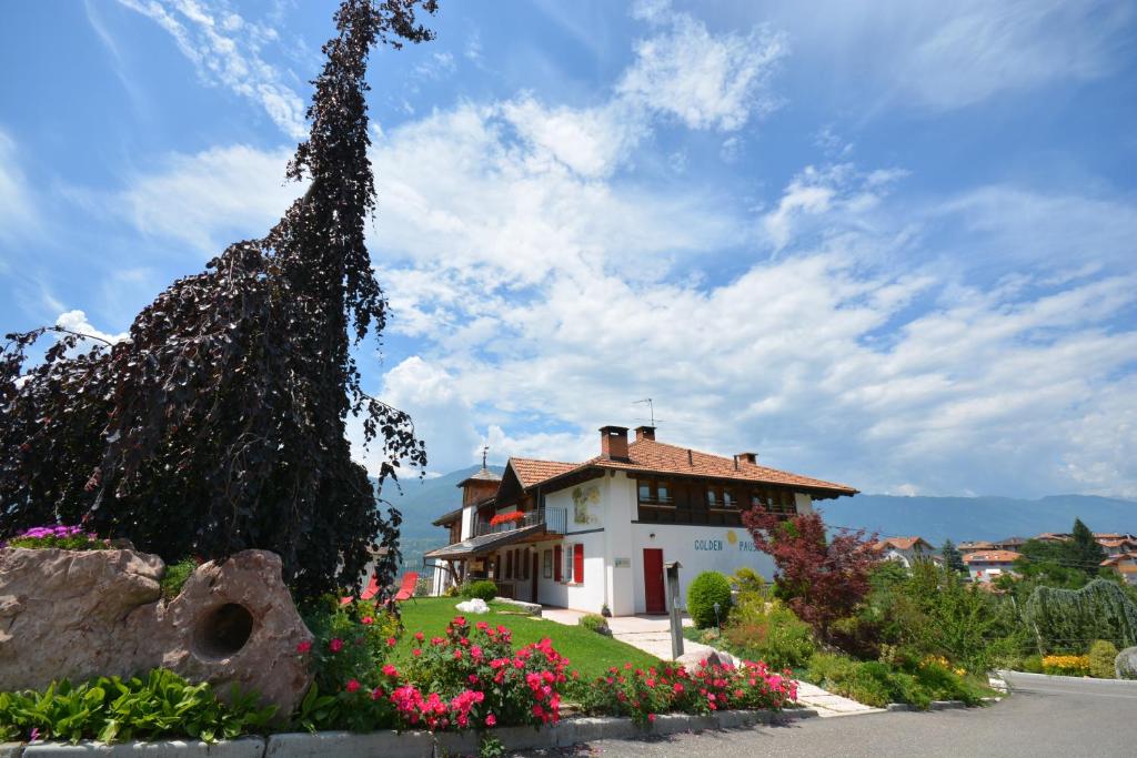 una casa con un árbol y flores delante de ella en Agritur Golden Pause, en Ton