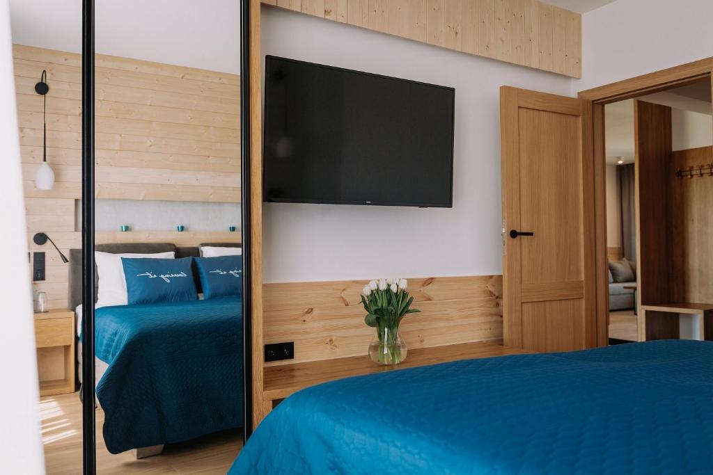 a bedroom with a blue bed and a flat screen tv at Royal Baltic Apartments in Darłówko