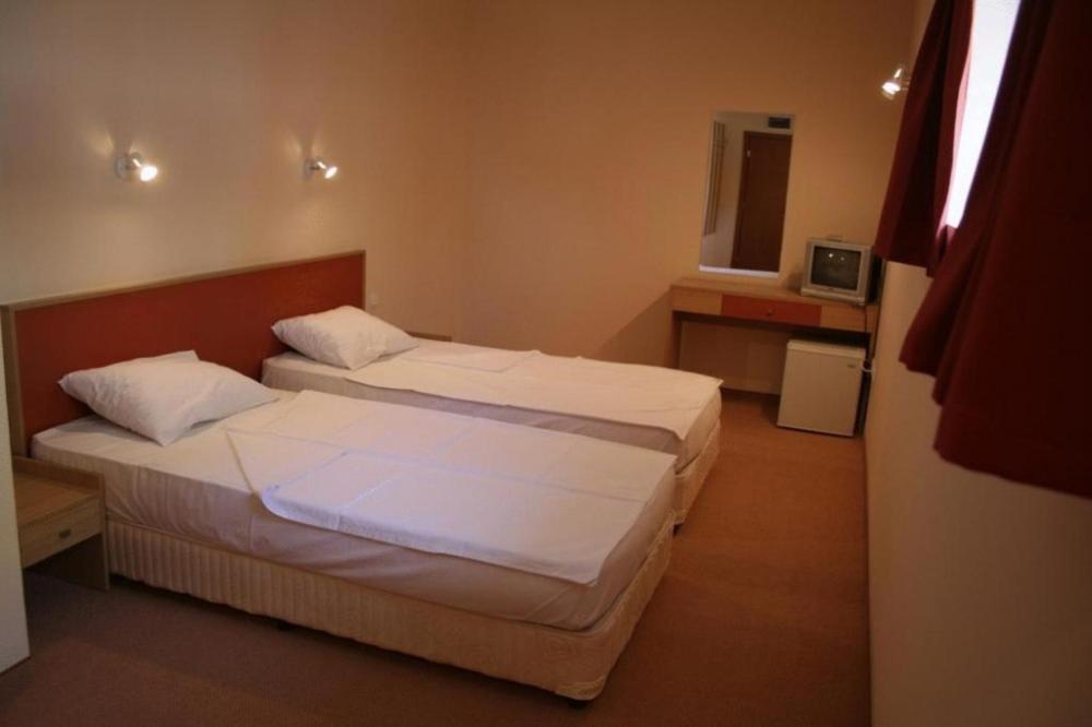 a bedroom with two beds and a tv in it at Hotel Nadia in Primorsko