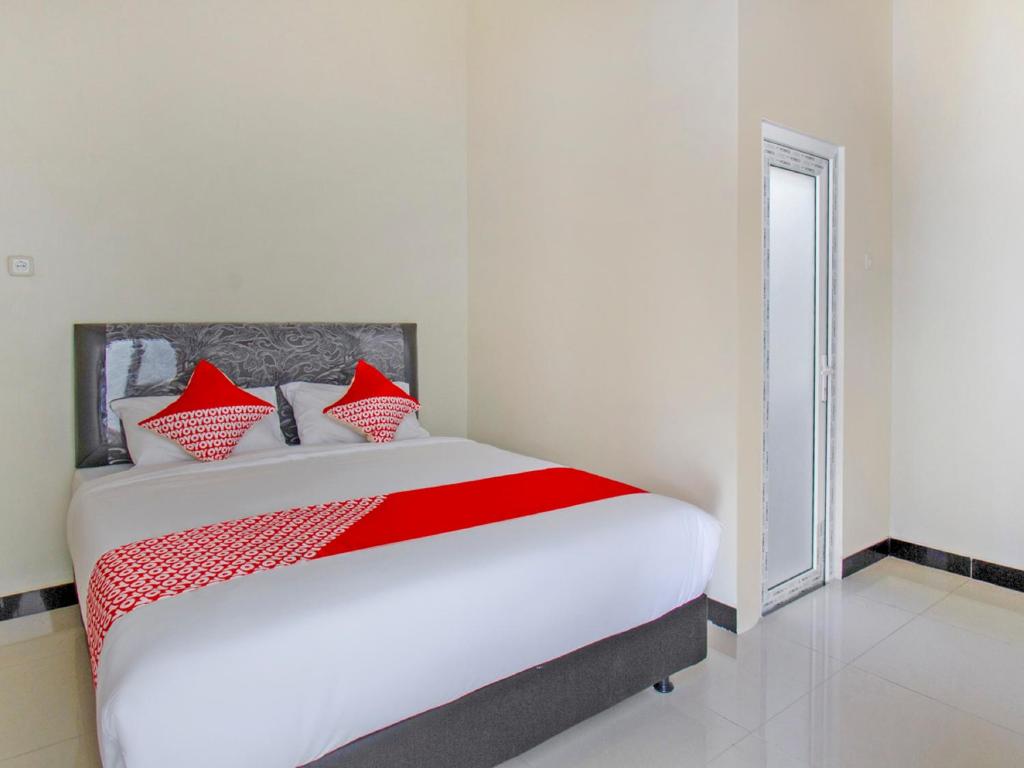 a bedroom with a white bed with red pillows at OYO 2753 Irma's Residence in Blitar