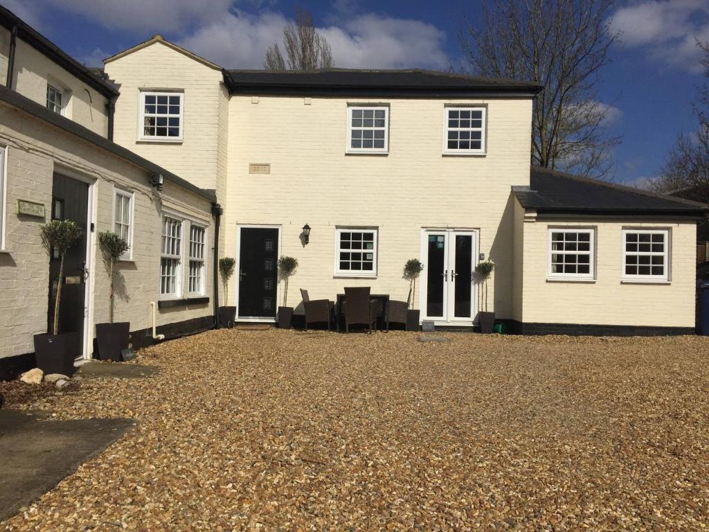a large white house with a gravel driveway at Courtyard Cottage - Great Paxton in Saint Neots