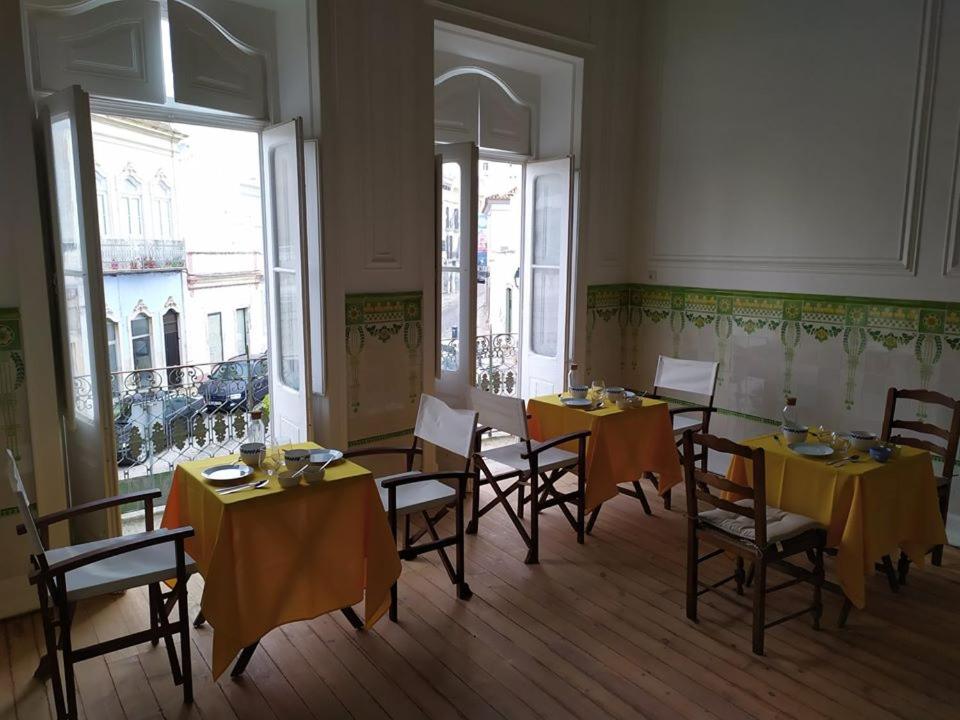 une salle à manger avec des tables, des chaises et un tissu de table jaune dans l'établissement OlhãOmirante Guesthouse, à Olhão