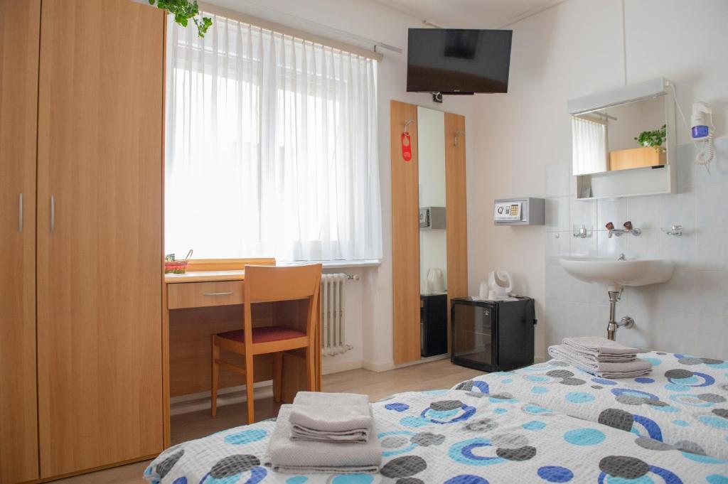 a bedroom with a bed and a desk and a sink at Garni Moderno in Bellinzona