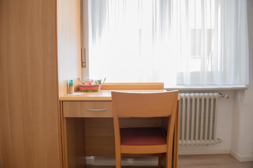 a wooden desk with a chair in front of a window at Garni Moderno in Bellinzona