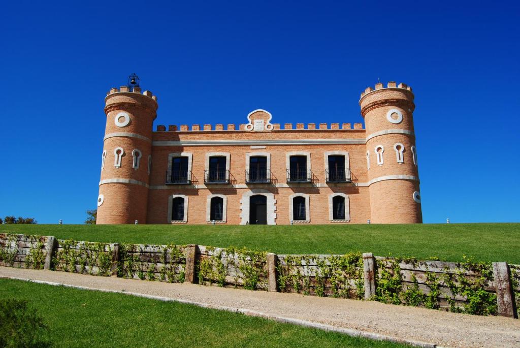 un château sur une colline avec une clôture devant lui dans l'établissement Castillo de Monte la Reina Posada Real & Bodega, à Toro