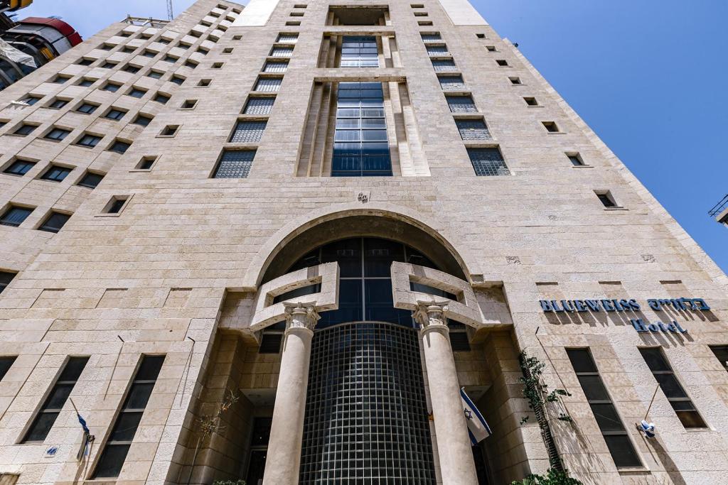 un grand bâtiment avec un escalier menant à celui-ci dans l'établissement Hotel Blue Weiss, à Netanya