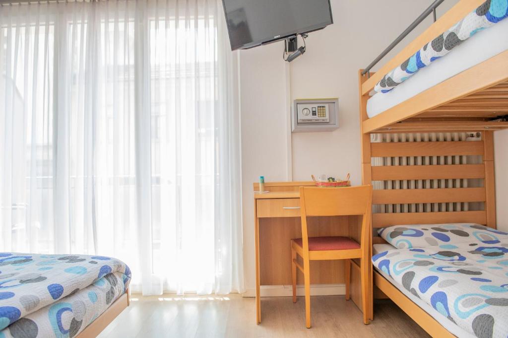 a bedroom with a bed and a desk and a bunk bed at Garni Moderno in Bellinzona