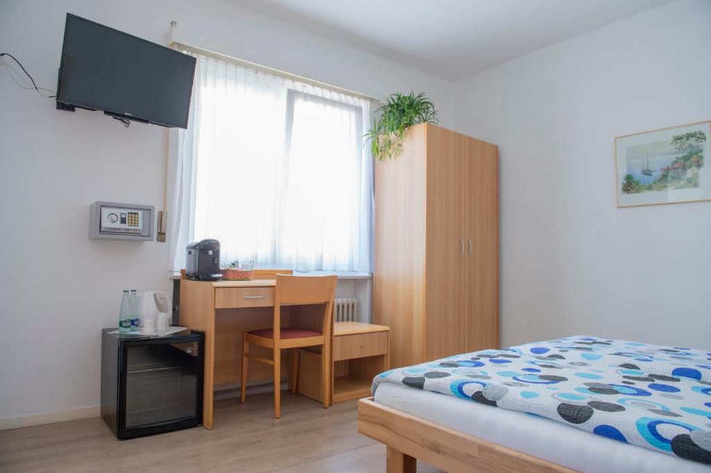 a bedroom with a bed and a desk and a window at Garni Moderno in Bellinzona