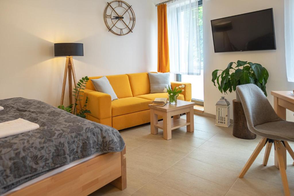 Calma في لوهاتشوفيتسا: غرفة معيشة مع أريكة صفراء وتلفزيون