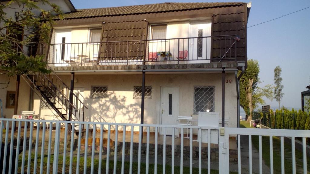 uma casa com uma cerca branca em frente em Vízparti apartmanok em Szántód