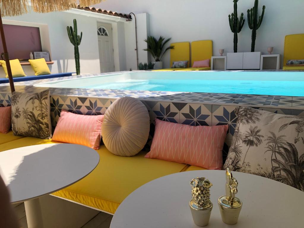 una piscina con almohadas en un banco frente a una piscina en Hôtel Mademoiselle, en Juan-les-Pins