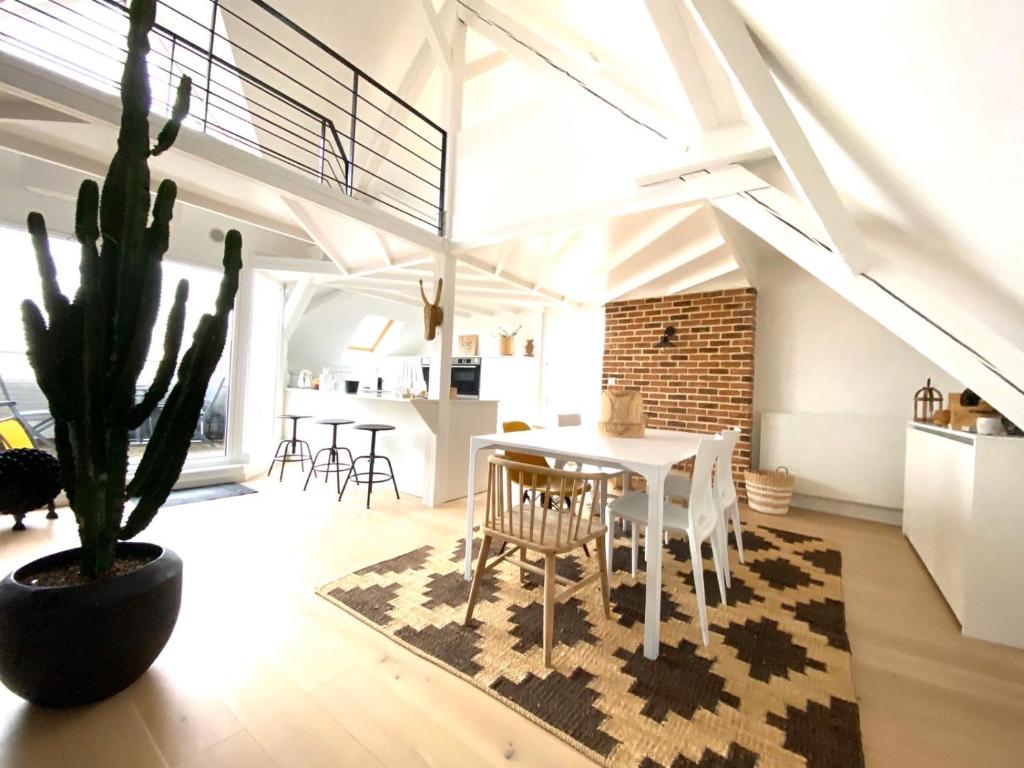 a white dining room with a table and a cactus at LA CLE DES TOITS in Colmar