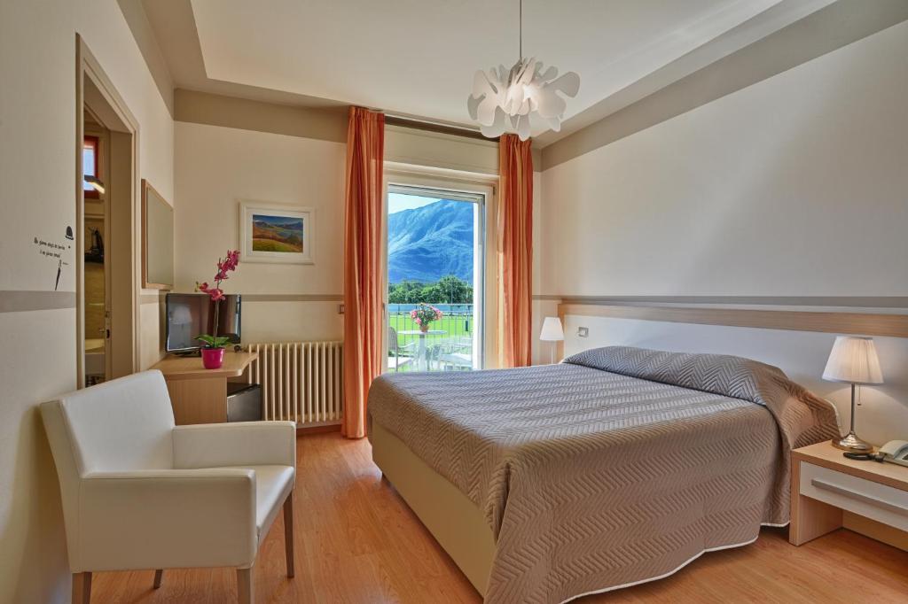 1 dormitorio con 1 cama, 1 silla y 1 ventana en Hotel Europa - Sorico, en Sorico