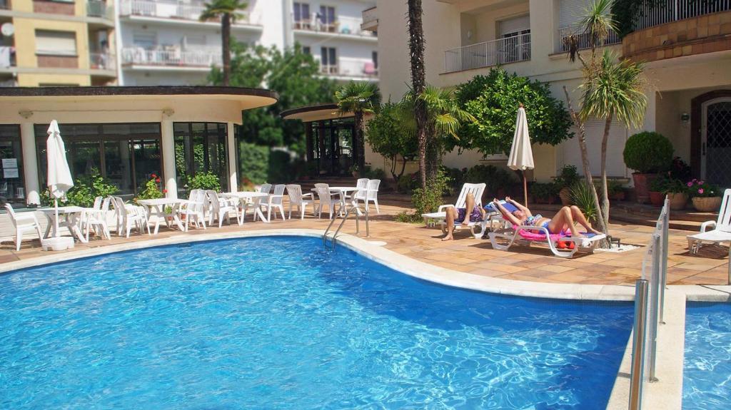 a woman laying in lawn chairs next to a swimming pool at Hotel Mireia in Lloret de Mar