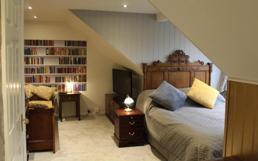 a bedroom with a bed and a tv and book shelf at Haydn House in Glastonbury
