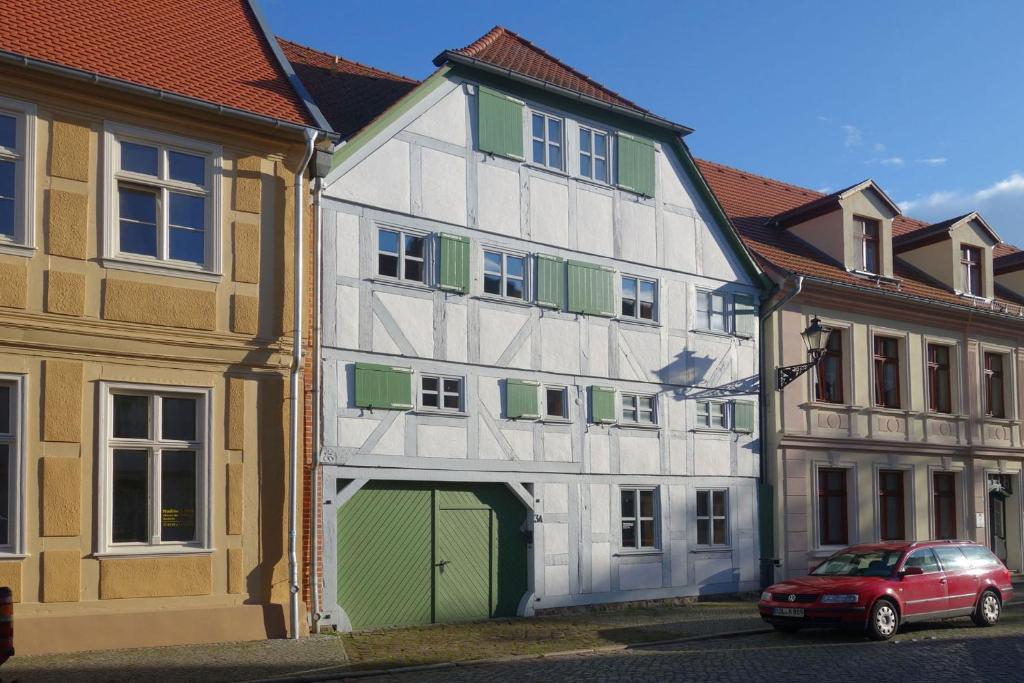 un edificio blanco y verde con un coche aparcado delante en Brezelhaus, en Tangermünde