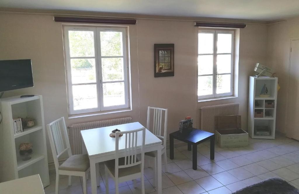 uma sala de estar com uma mesa e cadeiras e duas janelas em Le MAELY, studio au calme, centre de Honfleur (linge fourni) em Honfleur