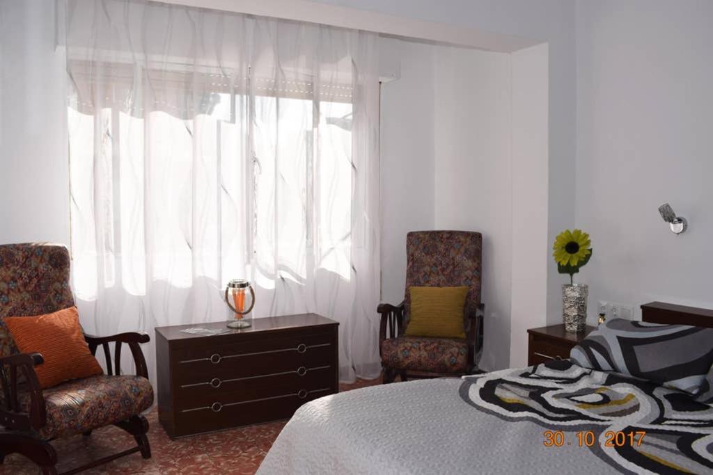 a bedroom with a bed and two chairs and a window at Apartamento en el centro de Alicante in Alicante