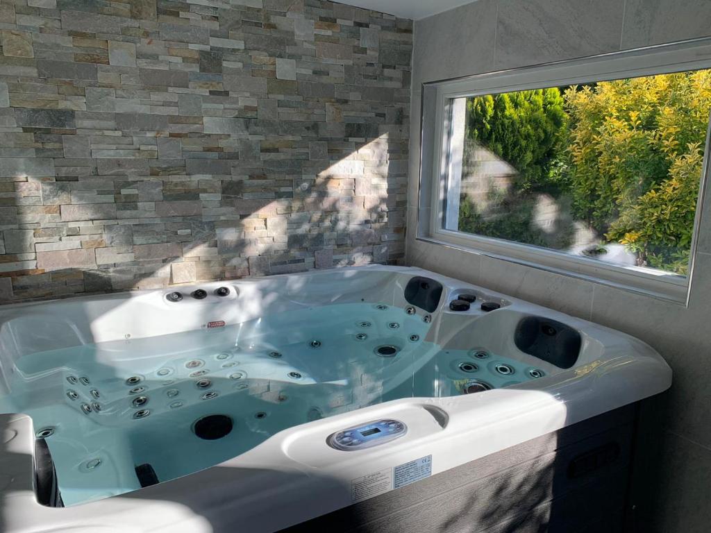 La salle de bains est pourvue d'une grande baignoire et d'une fenêtre. dans l'établissement Relax & Spa - Séjour Romantique, à Margny-lès-Compiègne