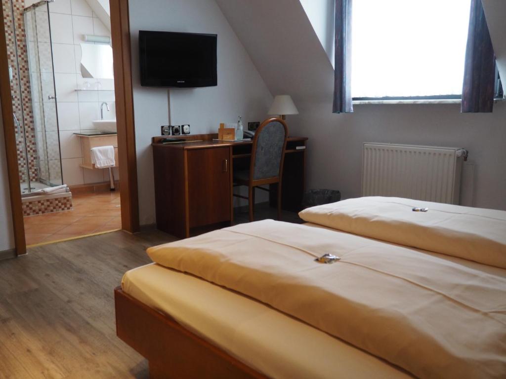 a bedroom with two beds and a desk and a television at Hotel Bienefeld in Korschenbroich