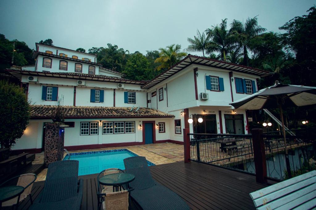 a house with a pool and a deck with chairs at Hotel Solar Das Lajes in Ouro Preto