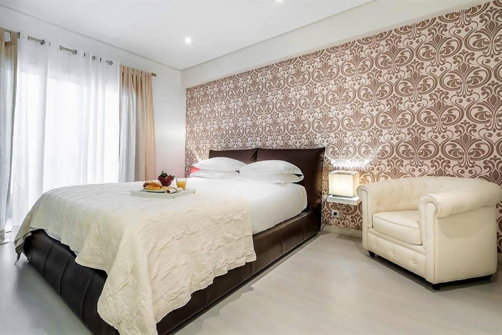 a bedroom with a large bed and a chair at InLoveApartments - City Center With Charm in Lisbon