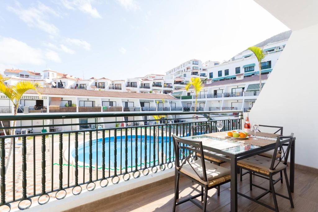 balcón con mesa y sillas y piscina en BuenaVista in Los Cristianos, en Arona