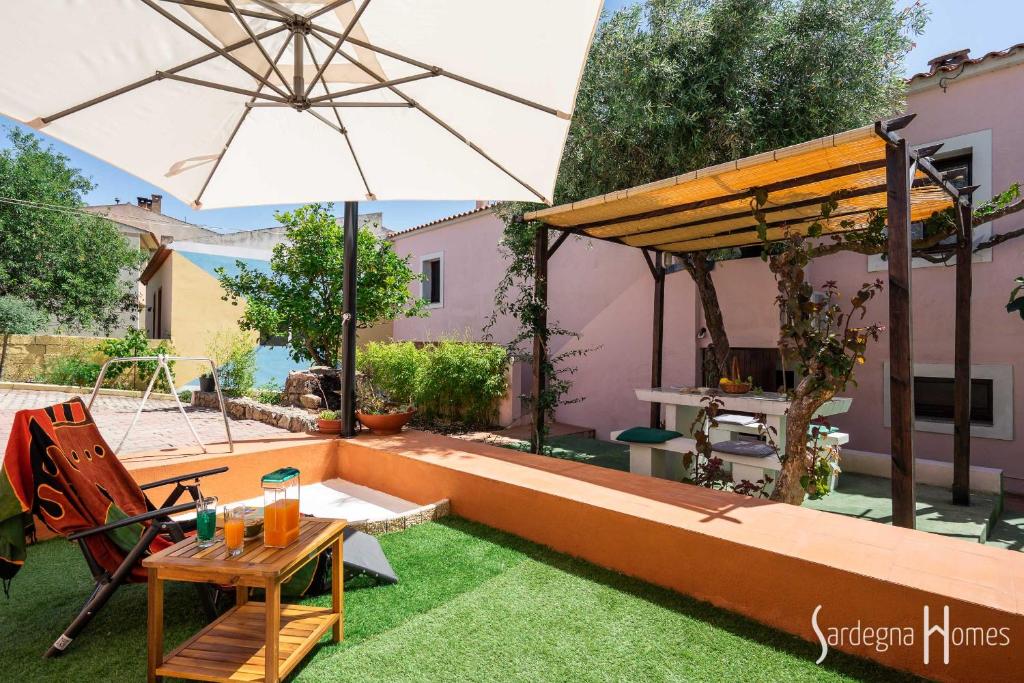 un patio con mesa, sombrilla y césped en Sardegna Homes Casa Rosa, en Badesi