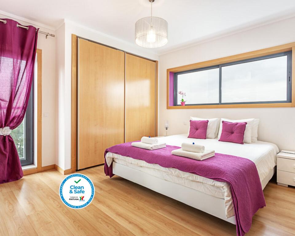 um quarto com uma cama grande e lençóis roxos em Privilege Apartment Galichet with Rooftop Pool, Village Marina - Olhão em Olhão