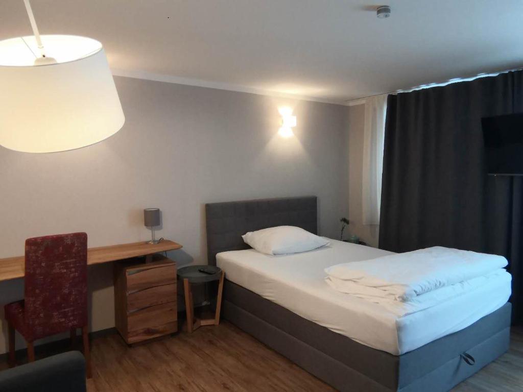 a bedroom with a bed and a desk and a chair at Motel Q - das kleine Stadthotel in Dingolfing