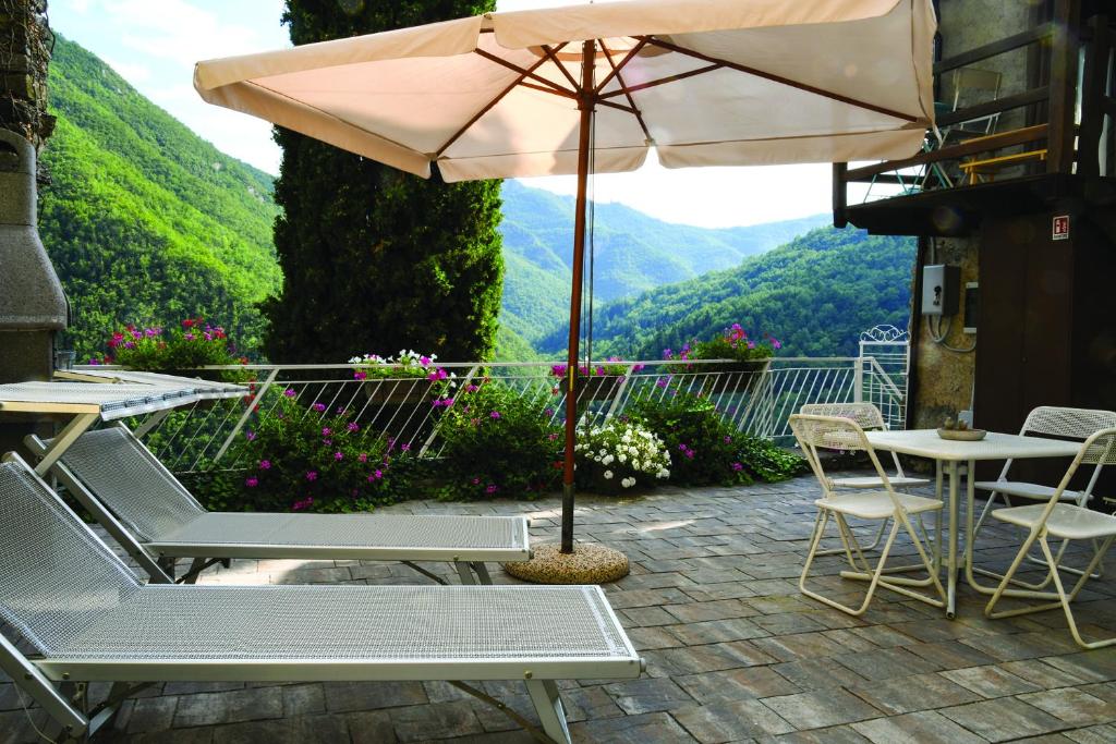 a patio with an umbrella and tables and chairs at Agriturismo Nonnamelia in Nasino