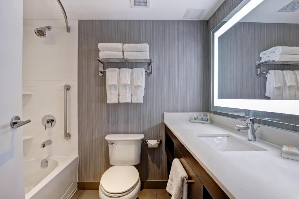 a bathroom with a toilet and a sink and a tub at Holiday Inn - Mississauga Toronto West, an IHG Hotel in Mississauga