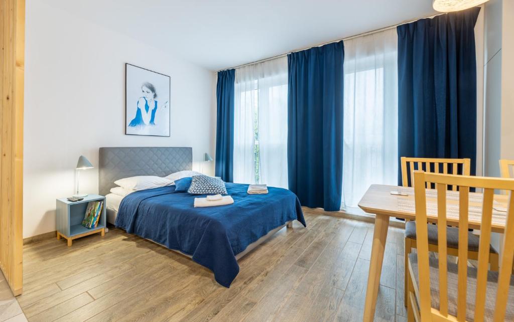a bedroom with a bed with blue curtains and a table at BierzCzadowy Apartament in Ustrzyki Dolne