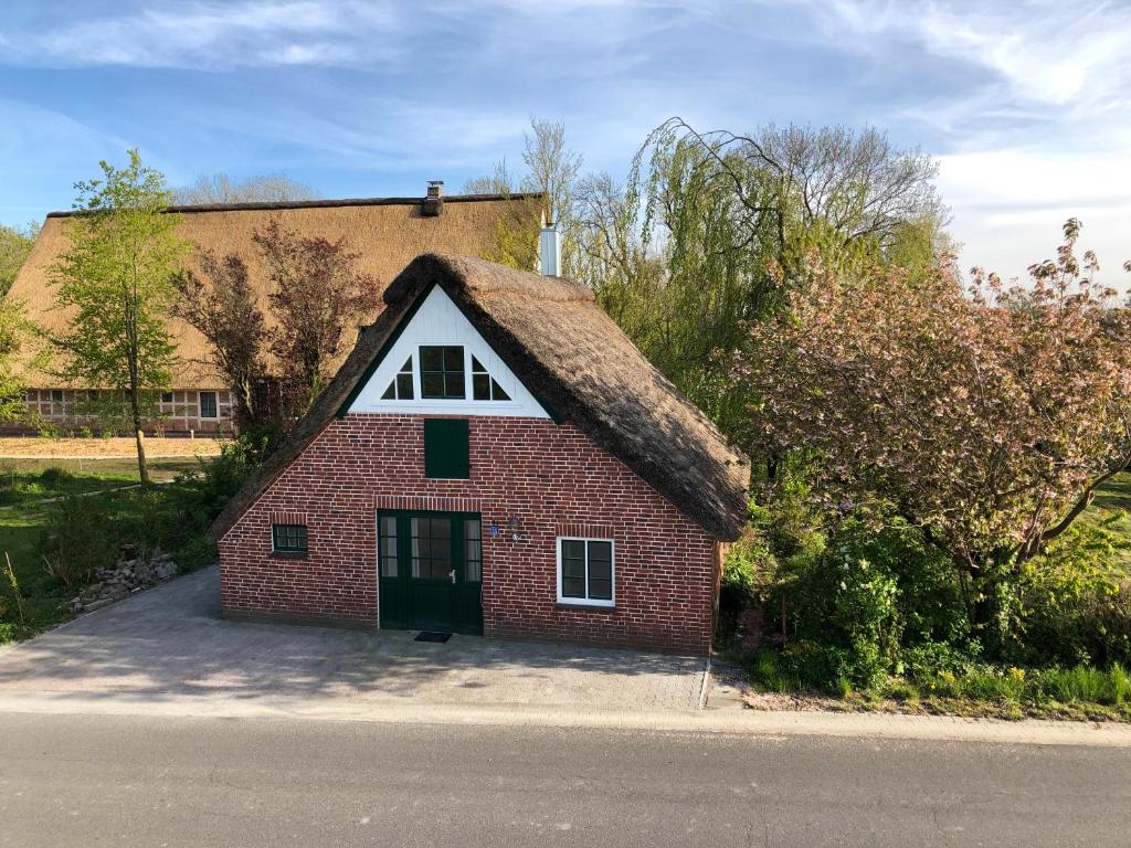 a small red brick house with a thatched roof at Haus Käthe am Deich in Balje