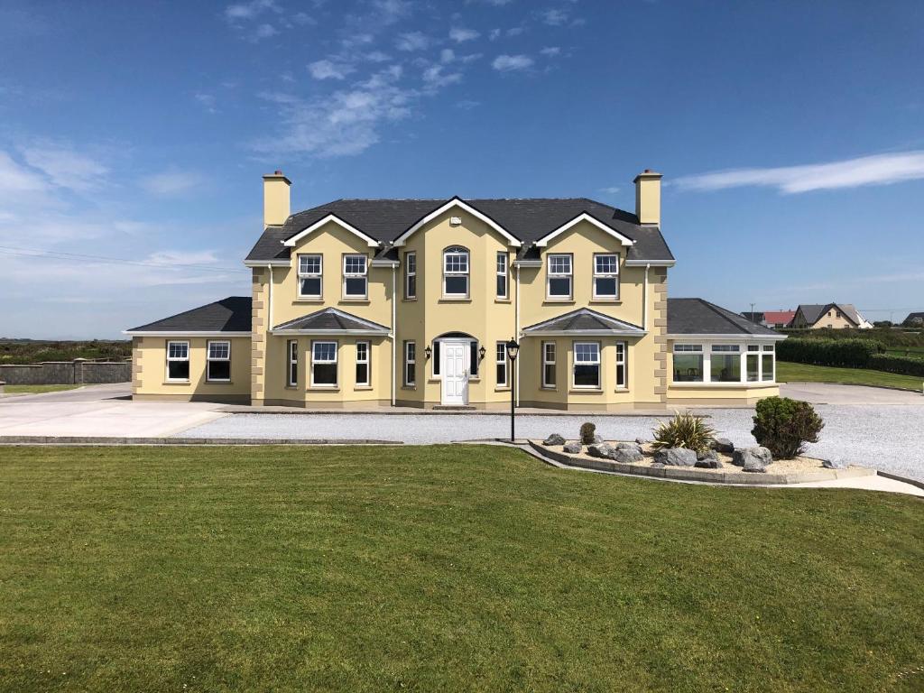 duży żółty dom z trawnikiem przed nim w obiekcie Seashore B&B w mieście Ballybunion