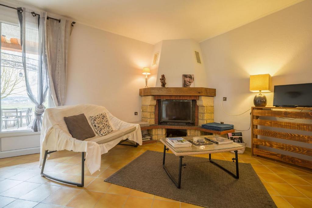 a living room with a fireplace and a chair and a table at CHAMBRES D&#39;HOTES 2 à 4p ou GITE DE GROUPE 15p, 7 ch, 6 sdb, parc et salle de réception in Villeneuve-de-Berg