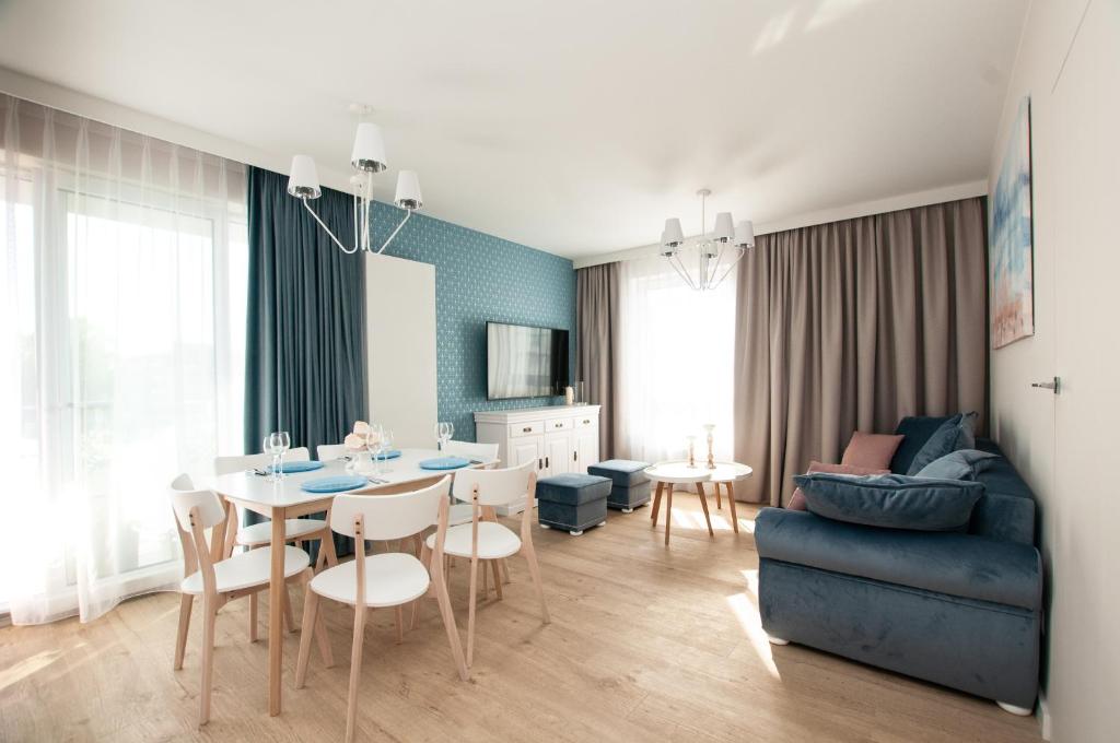 a living room with a table and a blue couch at Komfortowy Apartament PASTELOWY - 2 sypialnie in Kołobrzeg