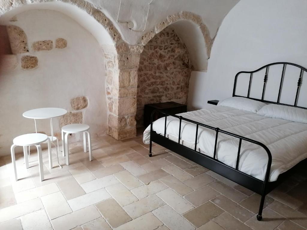 een slaapkamer met een bed en een tafel en stoelen bij Elda Guest House in Ostuni