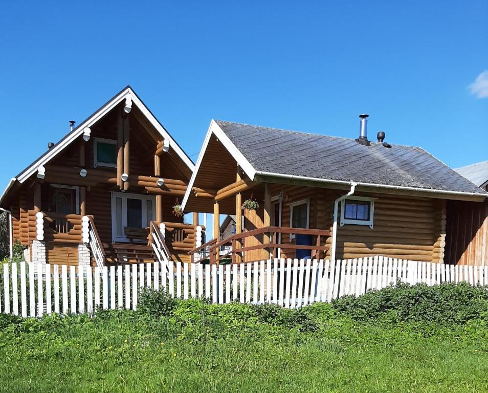 a wooden house with a fence in front of it at Дом с баней на берегу озера in Ferapontovo